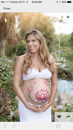 a pregnant woman in a white dress is holding her belly with flowers painted on it