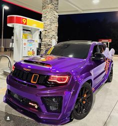 a purple sports utility vehicle parked in front of a gas station with a bow on it's hood