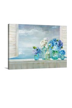 blue and white flowers in vases sitting on a window sill by the ocean