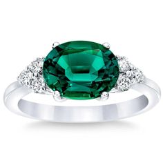 an emerald and diamond ring on a white background