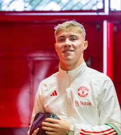 a young man holding a soccer ball in front of a red wall