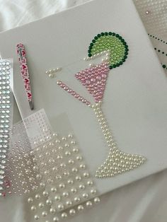 the beaded artwork is being displayed on the table with pearls and other beads around it