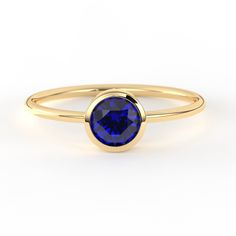 a yellow gold ring with a blue sapphire stone on the center and a thin band