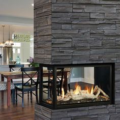 a fire place in the middle of a living room next to a dining room table