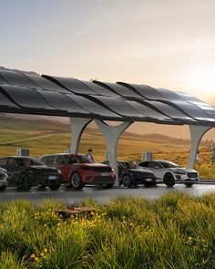 several cars are lined up in front of a solar powered gas station with the sun setting behind them