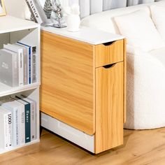 a white couch sitting next to a wooden book shelf with books on top of it