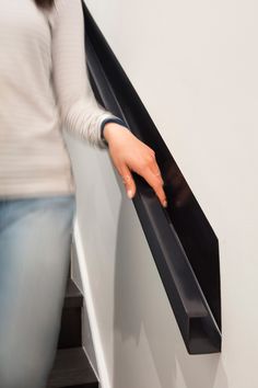 a woman is holding onto the edge of a stair rail with her hand on it