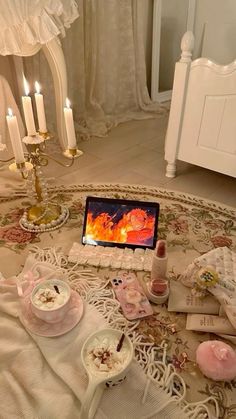 a table topped with lots of food and candles next to a laptop on top of a bed