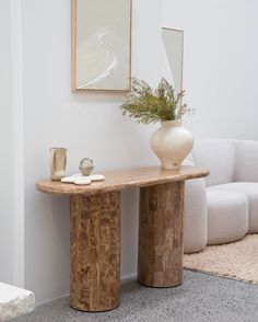 a white vase sitting on top of a wooden table next to a couch in a living room