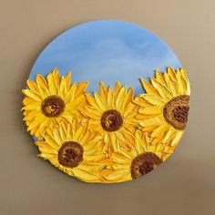 a painting of yellow sunflowers in front of a blue sky on a circular mirror