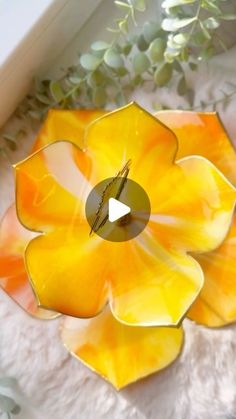 an orange and yellow flower shaped object sitting on top of a white blanket next to a plant