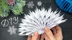 someone is holding an origami snowflake in front of some paper decorations