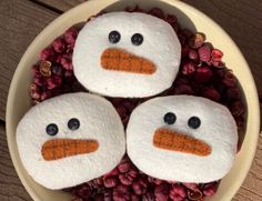 three snowmen made out of felt sitting in a bowl filled with berries and flowers