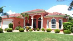 a pink house with palm trees in the front yard and landscaping on the lawn area