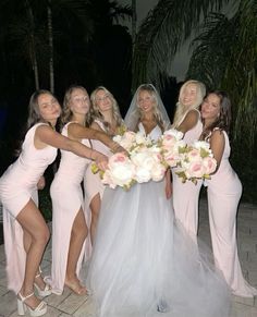 a group of women standing next to each other in front of palm trees and flowers