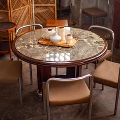 a marble table with chairs around it and two vases sitting on top of the table