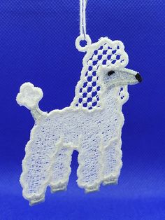 a white poodle ornament hanging from a string on a blue background,