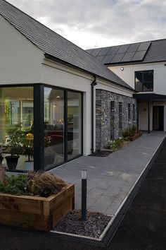 an outside view of a house with large windows and plants in the front garden area