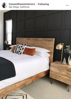 a bedroom with black walls and white bedding, wooden headboard and night stand