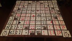 a wooden table topped with playing cards on top of a hard wood floor next to a wall