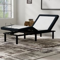 an adjustable bed frame in a living room with white walls and rugs on the floor