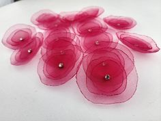 some pink flowers on a white surface with water droplets in the middle and one flower surrounded by smaller petals