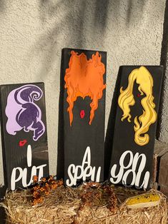 three painted wooden signs sitting on top of hay