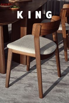 a dining room table with two chairs and a bowl of fruit on the table next to it