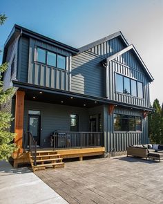 a large gray house sitting on top of a wooden deck