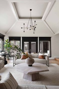 a living room filled with furniture and a chandelier hanging from the skylight