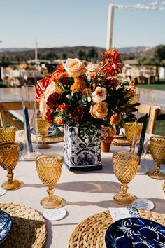 the table is set with blue and white plates, silverware, and orange flowers