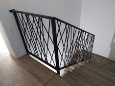 an iron stair railing with wooden floors and white walls