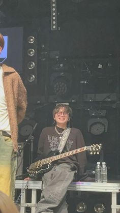 two men standing on stage with guitars in front of them