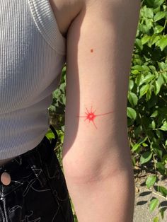 a woman's arm with a red star tattoo on the left side of her arm