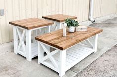 two wooden tables sitting next to each other on top of a cement floor near a building