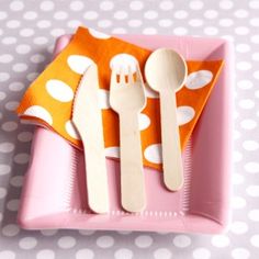 a pink plate topped with wooden utensils on top of a polka dot table cloth