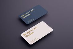 two business cards sitting next to each other on top of a black surface with gold lettering