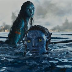 two people in the water with blue paint on their face and body, one woman has yellow eyes