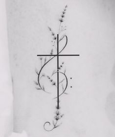 a cross tattoo on the back of a woman's upper arm with vines and leaves