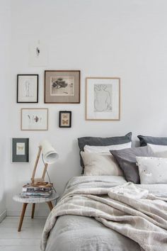 a bed room with a neatly made bed and pictures hanging on the wall above it