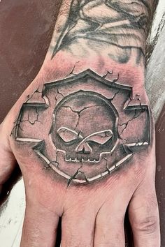 a man's hand with a skull and shield tattoo on it