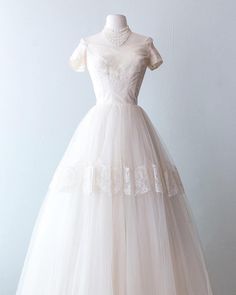 a white wedding dress on a mannequin with an off the shoulder neckline