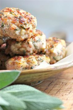 some meat patties are stacked on top of each other in a bowl with sage leaves