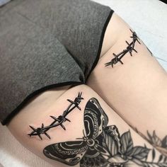 a woman's thigh with barbed wire and butterfly tattoos on her legs, while holding an umbrella