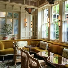 a living room filled with lots of furniture next to large windows and potted plants