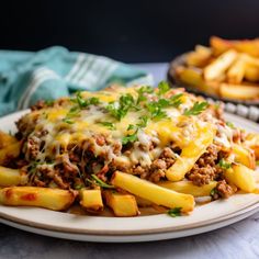 a white plate topped with cheesy french fries covered in cheese and meat sauce