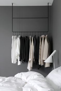 a rack with clothes hanging from it next to a bed