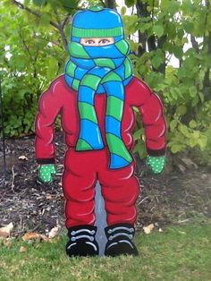 a statue of a person wearing skis and a scarf on the grass in front of some trees