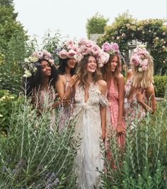 a group of women standing next to each other in front of some bushes and flowers