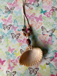 a shell with beads is hanging from a string on a colorful wallpapered background